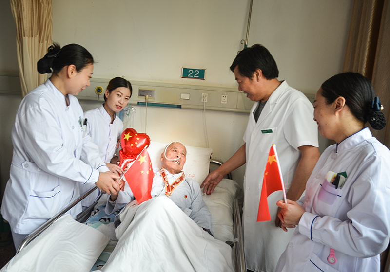 4峰峰总医院国庆节当日内三科病房里医护们为93岁的患者秦武平带上中共中央、国务院中央军委宣告的国庆70周年留想章并和他一路欢度国庆，秦爷爷曾参与过南征惫亟、孟良崮战争、淮海战争、抗美援朝是一名老武士、老革命 作者：肖建华(2).jpg